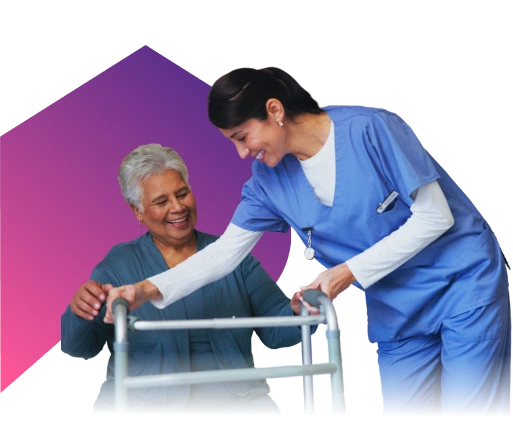 A nurse in scrubs is helping an older woman use a walker, both smiling warmly at each other.