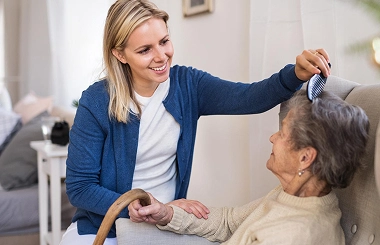 Caregiver brushing elderly woman’s hair