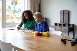 Professional caregiver helping an elderly woman with daily tasks and providing companionship at home.