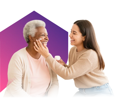 Two women, one elderly with gray hair and one younger with brown hair, smile as the younger woman applies cream to the older woman's face. Background is a purple and pink gradient.