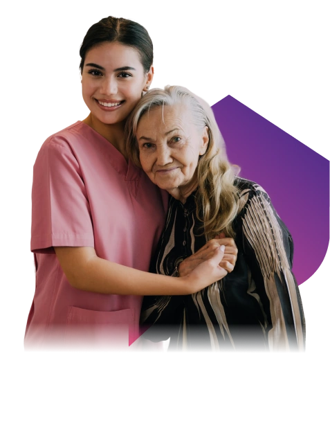 A young woman in pink scrubs warmly embraces an elderly woman with long gray hair, both smiling, against a black background with a purple gradient shape.