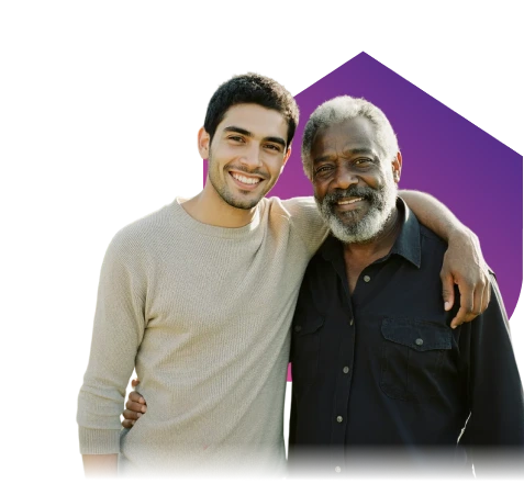 A young man and an older man, both smiling, stand arm in arm against a black background with a purple geometric shape. The mood is warm and friendly.