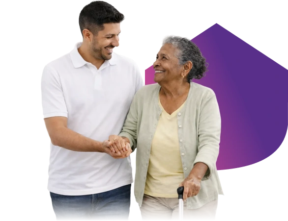 Caregiver holding hands with an elderly woman using a cane, smiling and walking together.