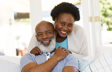 Smiling senior couple sitting close together on a couch at home