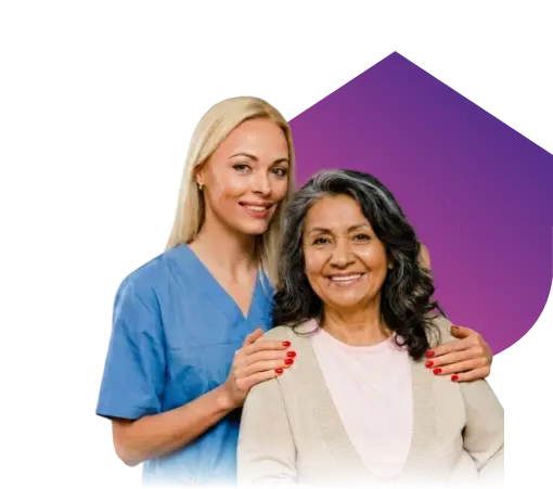 A smiling nurse in blue scrubs standing behind and embracing an elderly woman against a purple geometric background