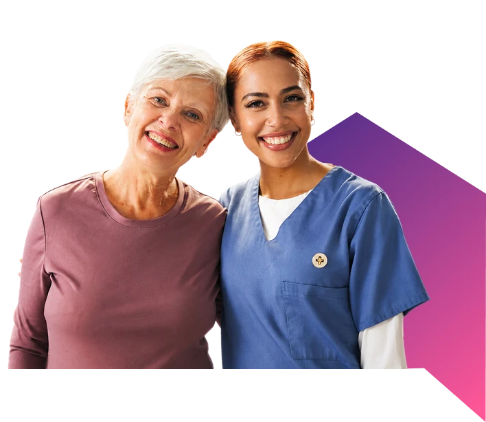 Smiling elderly woman standing arm-in-arm with a cheerful female nurse in blue scrubs against a purple gradient backdrop.