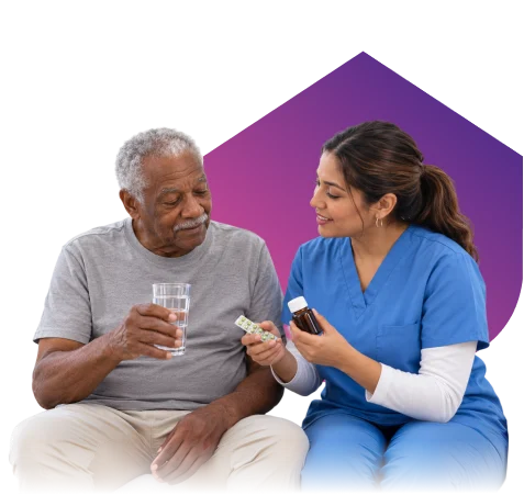 Caregiver explaining medication to a senior man holding a glass of water